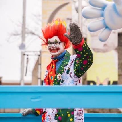 Ross Morton in clown costume waving at the Santa Claus Parade